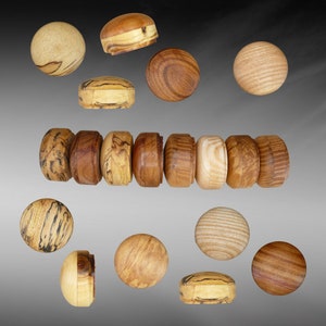 May include: A collection of wooden knobs with various wood grain patterns and colors. The knobs are round and have a smooth finish. Some of the knobs are arranged in a row, while others are scattered around the image.