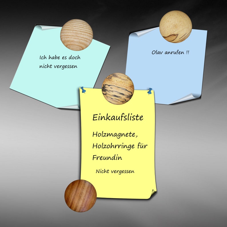 May include: Yellow sticky note with the text "Einkaufsliste" and a list of items to buy: "Holzmagnete, Holzohrringe f&uuml;r Freundin, Nicht vergessen". Three wooden round magnets are holding the notes to a gray surface.