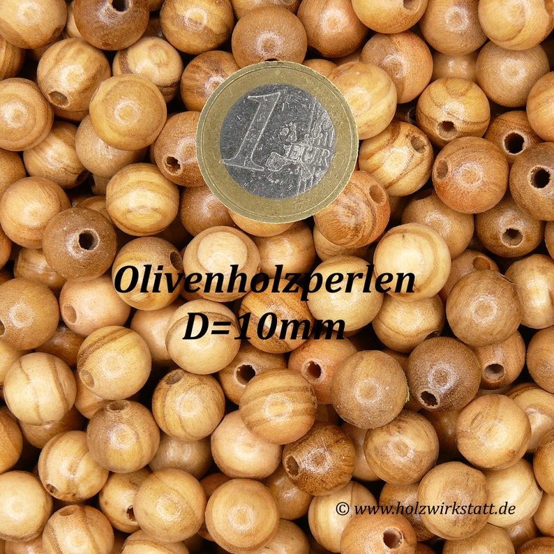 May include: A close-up of a pile of round, light brown wooden beads with a 1 Euro coin for scale. The beads are 10mm in diameter and are labeled "Olivenholzperlen D=10mm".