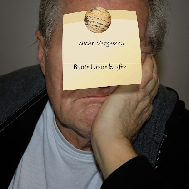 May include: A man with a yellow sticky note on his forehead. The note has a drawing of a wooden sphere and the text "Nicht Vergessen Bunte Laune kaufen".