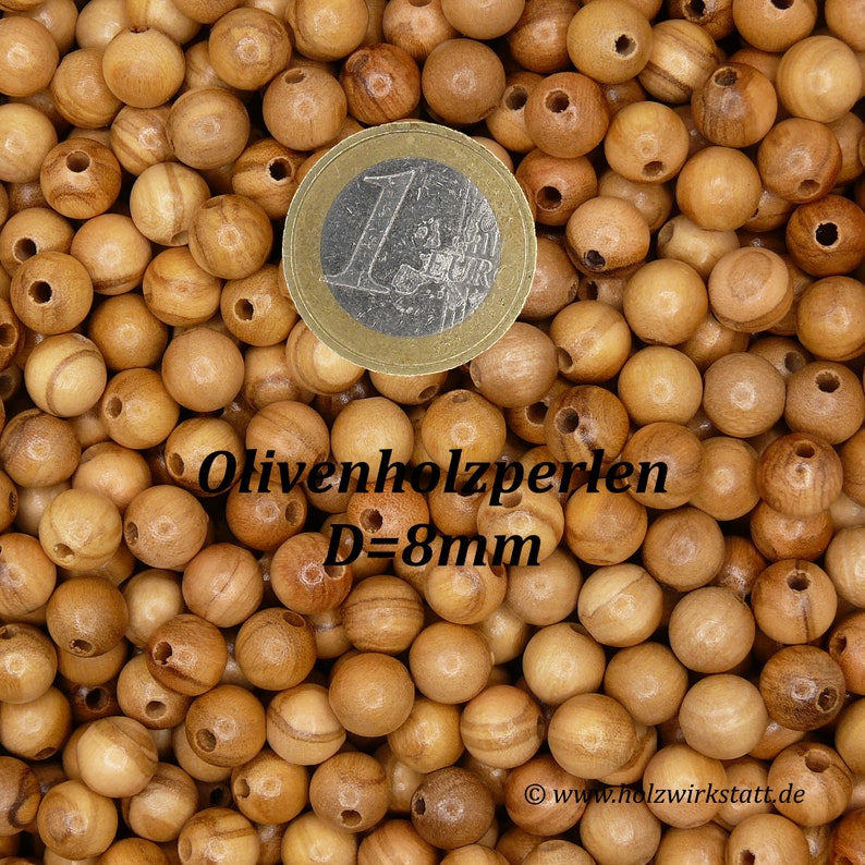May include: A close-up image of a pile of natural wood beads. The beads are round and have a hole in the center. The beads are 8mm in diameter. A Euro coin is included for size reference. The text "Olivenholzperlen D=8mm" is visible in the image.