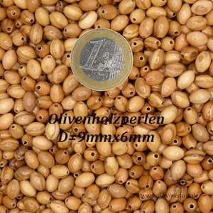 May include: A close-up image of a pile of oval-shaped wooden beads. The beads are a light brown color with darker brown streaks. A Euro coin is in the center of the image for scale. The text "Olivenholzperlen D=9mm x 6mm" is visible in the image.