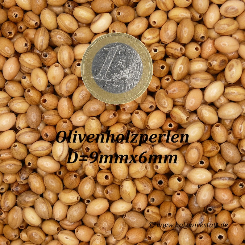 May include: A close-up image of a pile of oval-shaped wooden beads. The beads are a light brown color with darker brown streaks. A Euro coin is in the center of the image for scale. The text "Olivenholzperlen D=9mm x 6mm" is visible in the image.