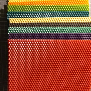 May include: A stack of colourful honeycomb foundation sheets for beekeeping. The sheets are made of beeswax and are used to help bees build their honeycomb.