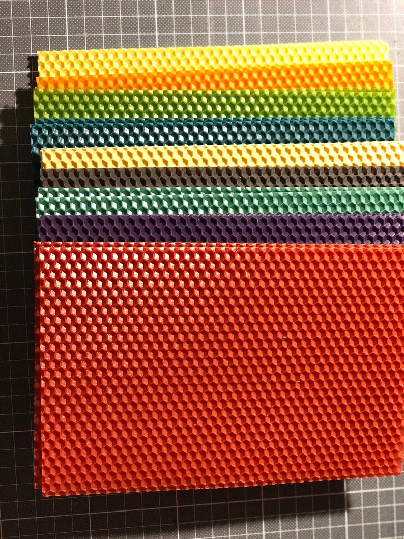 May include: A stack of colourful honeycomb foundation sheets for beekeeping. The sheets are made of beeswax and are used to help bees build their honeycomb.