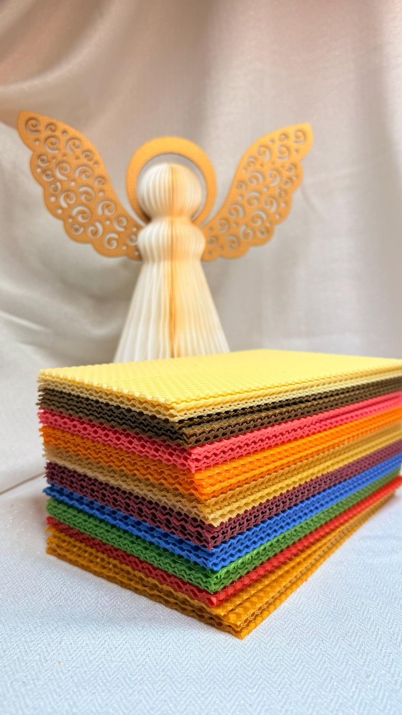 May include: A stack of colourful honeycomb wax sheets in various shades of yellow, orange, red, brown, green, and blue. The sheets are stacked in a staggered pattern, creating a visually appealing display.