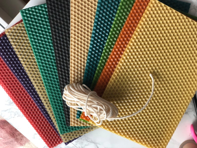 May include: A set of eight honeycomb wax sheets in various colours, including red, purple, green, black, yellow, orange, and teal, with a roll of white twine.