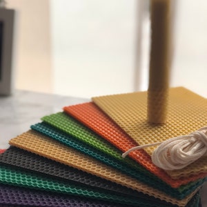 May include: A set of colourful honeycomb wax sheets for candle making, with a white cotton wick and a single beeswax candle.
