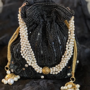 Könnte beinhalten: Eine schwarze Perlen-Kordeltasche mit einer goldenen Kette und Perlen-Akzenten. Die Tasche hat eine runde Form und ist mit Pailletten verziert.