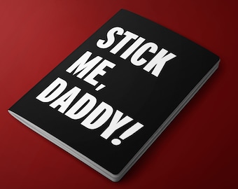 May include: A black notebook with the text "STICK ME, DADDY!" printed in white.