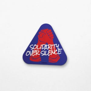 Triangle-shaped blue sticker featuring two red hands clasped in unity. White text reads "Solidarity Over Silence," inspired by the 1969 "Come Together in Peace" protest poster.