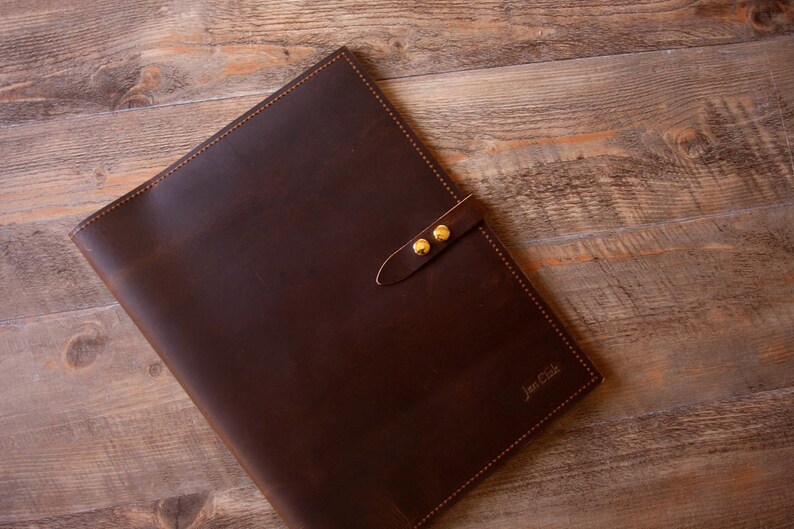 May include: A brown leather folder with a gold clasp and the text "Jim Cole" embossed on the front.