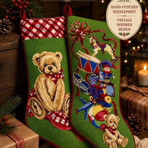 May include: Two green hand-stitched needlepoint Christmas stockings featuring vintage-inspired designs. One stocking displays a teddy bear, while the other shows a rocking horse, drum, and toys. Both have red and white plaid cuffs and hanging loops.