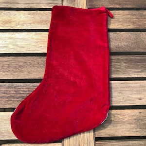 May include: A red velvet Christmas stocking with a white cuff and a loop at the top.