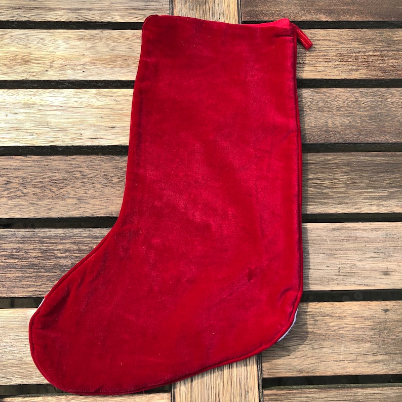 May include: A red velvet Christmas stocking with a white cuff and a loop at the top.