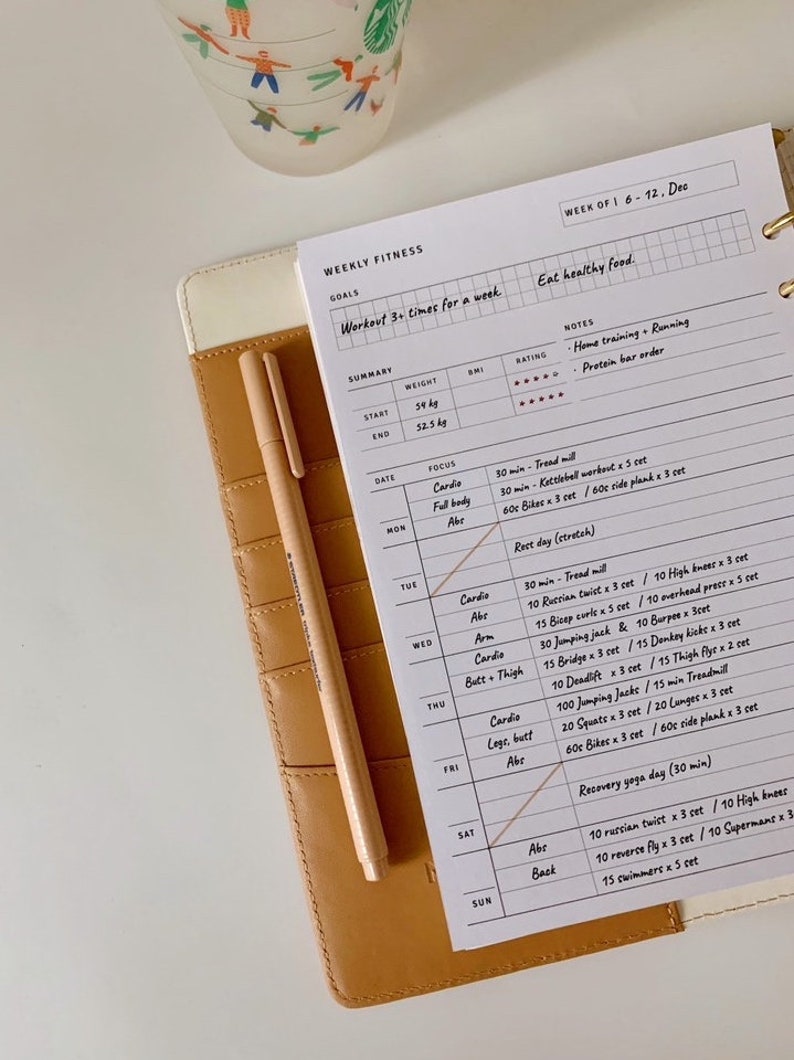 May include: A weekly fitness planner with a white background and black grid lines. The planner includes a section for goals, a summary of weight and BMI, and a daily workout schedule. The workout schedule includes cardio, abs, arm, butt and thigh, legs and butt, and back exercises. The planner also includes a section for notes and a rating system.