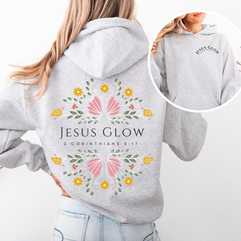 May include: Gray hooded sweatshirt with a floral design on the back. The design features pink flowers, yellow flowers, and green leaves. The text "JESUS GLOW" and "2 CORINTHIANS 5:17" is printed on the back of the sweatshirt.