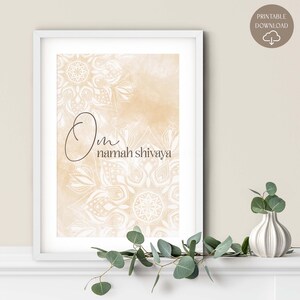 May include: Framed art print featuring the text "Om namah shivaya" in elegant script. The artwork has a beige watercolor background with white mandala designs. The print is in a white frame, suitable for home decor.