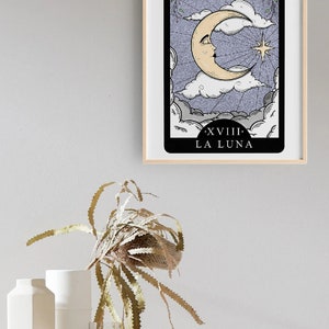 Pode incluir: Um cart&atilde;o de tar&ocirc; com uma borda preta e um fundo branco. O cart&atilde;o representa uma lua crescente com um rosto em um c&eacute;u nublado. O cart&atilde;o &eacute; rotulado como "XVIII. LA LUNA".