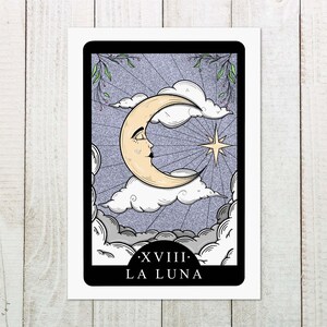 Pode incluir: Um cart&atilde;o de tar&ocirc; com uma lua crescente com um rosto, uma estrela e nuvens em um fundo roxo. O cart&atilde;o &eacute; rotulado como "XVIII: LA LUNA".