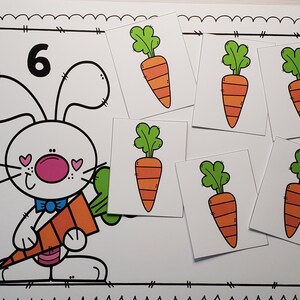 May include: A black and white illustration of a bunny holding a carrot. The number 6 is written above the bunny. There are six separate cards with illustrations of carrots on them.