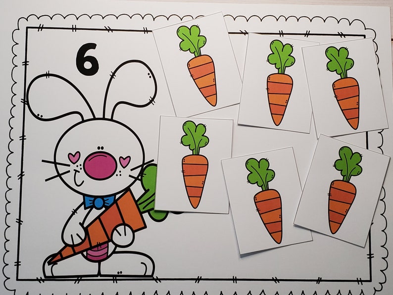 May include: A black and white illustration of a bunny holding a carrot. The number 6 is written above the bunny. There are six separate cards with illustrations of carrots on them.