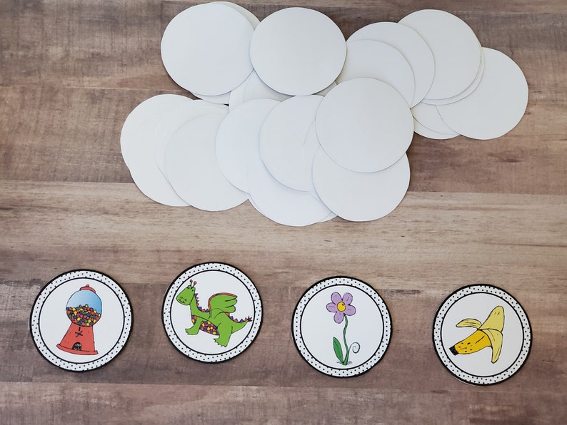Pode incluir: Quatro adesivos circulares brancos em branco com pontos pretos ao redor da borda. Cada adesivo tem uma imagem diferente no centro: uma m&aacute;quina de chicletes, um drag&atilde;o verde, uma flor roxa e uma banana amarela.
