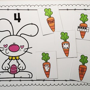 May include: A white bunny with pink cheeks and a yellow bow tie is holding a pink and white carrot. The number 4 is written above the bunny. There are five cards with carrots on them, each showing a different way to represent the number four: the word "four", four dots, a dice with four dots, a hand with four fingers, and four lines.