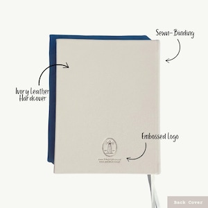 K&ouml;nnte beinhalten: Gebundenes Notizbuch aus elfenbeinfarbenem Leder mit einer gen&auml;hten Bindung und einem gepr&auml;gten Logo eines Leuchtturms auf dem hinteren Umschlag. Das Logo enth&auml;lt den Text "www.EstheticEdition.com" und "www.aesthetic-edi.com".