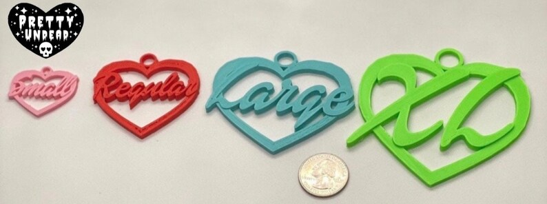 May include: Four heart-shaped ornaments in different sizes and colors. The smallest is pink and says "Small", the next is red and says "Regular", the largest is blue and says "Large", and the last is green and says "XL".