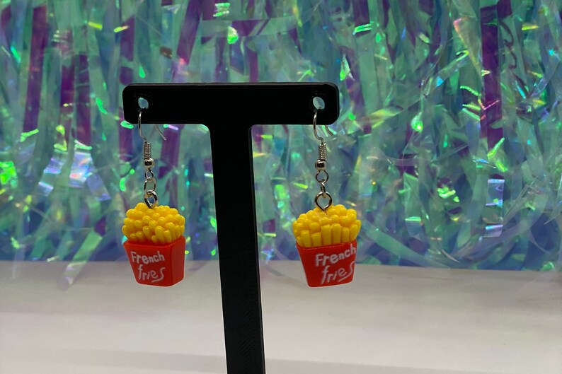 May include: A pair of dangle earrings featuring a red and yellow french fries charm with the text "French Fries".