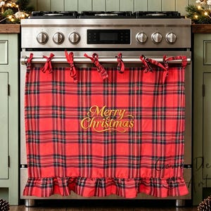 May include: A red and black tartan oven cover featuring a ruffled bottom edge and the gold embroidered text Merry Christmas. The fabric is secured to the oven handle with tied fabric strips, creating a decorative holiday accent for the kitchen.
