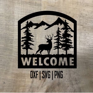 Könnte beinhalten: Schwarz-weiße Silhouette eines Hirsches, der vor einer Bergkette mit zwei Kiefern auf jeder Seite steht. Der Text "WELCOME" befindet sich unter dem Bild und der Text "DXF | SVG | PNG" darunter.