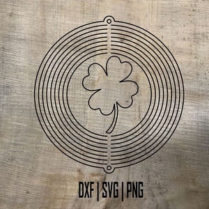 May include: Black and white four-leaf clover design inside a circle of concentric rings. The design is on a wood background. The text "DXF | SVG | PNG" is below the design.