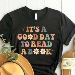 May include: Black t-shirt with the text "It's a good day to read a book" in colourful letters with flower accents.