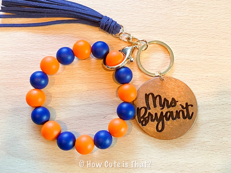 Peut inclure: Un porte-cl&eacute;s en perles bleues et orange avec une &eacute;tiquette en bois qui dit "Mme Bryant".