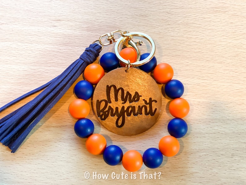 Peut inclure: Un porte-cl&eacute;s en perles bleues et orange avec une &eacute;tiquette en bois sur laquelle est inscrit "Mrs. Bryant".