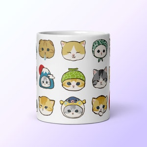 Puede incluir: Taza de cer&aacute;mica blanca con un patr&oacute;n de 12 gatos de dibujos animados que llevan diferentes sombreros y accesorios. Los gatos tienen diferentes expresiones, incluyendo feliz, triste y sorprendido.