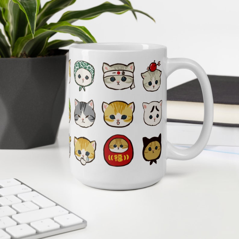 Puede incluir: Taza de cer&aacute;mica blanca con un dise&ntilde;o de 16 gatos de dibujos animados diferentes con diversas expresiones. Los gatos llevan sombreros, bufandas y otros accesorios. La taza tiene un asa negra.