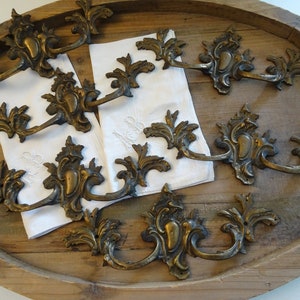 Peut inclure: Un ensemble de dix tirettes de tiroir en laiton antique avec des motifs floraux ornés. Les tirettes sont disposées sur une surface en bois.