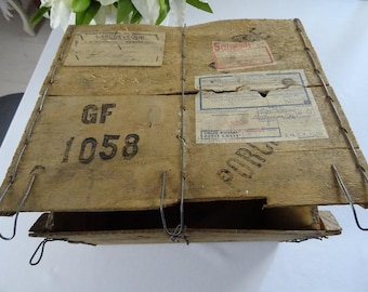 May include: A wooden box with a metal latch and a label that says "Colis Postal Petite Colis". The box is labeled with the number "GF 1058".