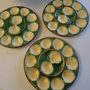 May include: Three vintage ceramic oyster plates with a green and white design. Each plate has a central well for sauce and 12 individual shell-shaped compartments.
