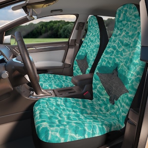 May include: Car seat covers featuring a teal water pattern and a black stingray design. The covers are fitted in a car, with the steering wheel and dashboard visible. The design has a marine theme.