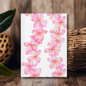 Può includere: Un taccuino bianco con un design floreale rosa e bianco. I fiori sono disposti in un motivo ripetitivo, creando un aspetto delicato e femminile.