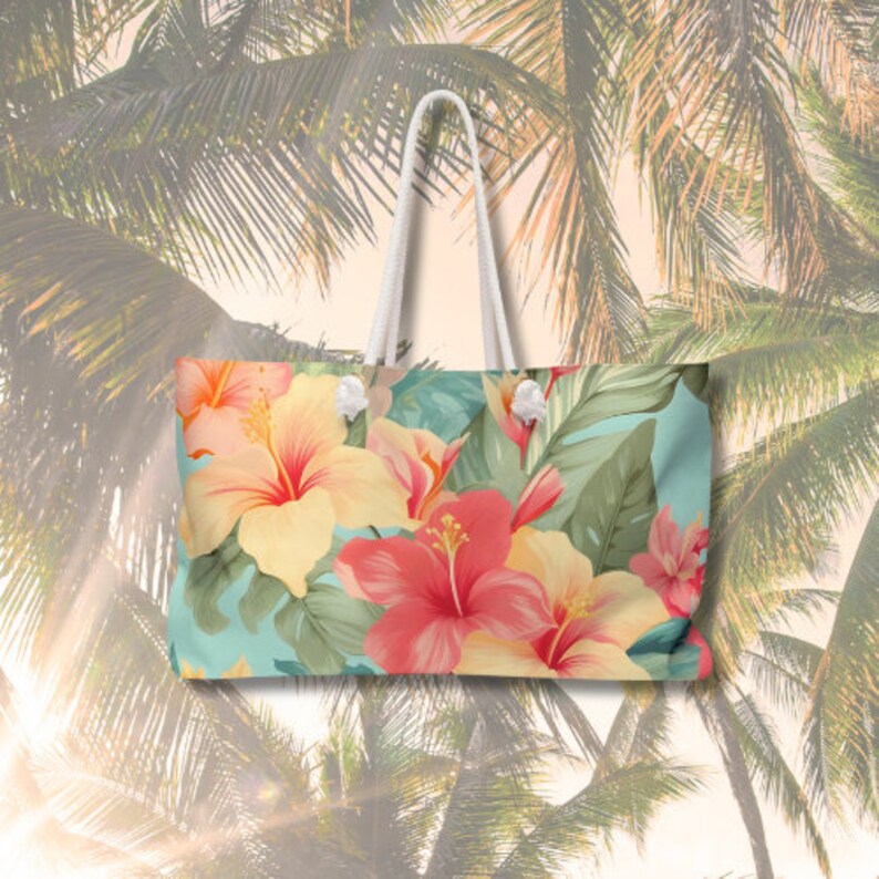May include: A white tote bag with a tropical floral print featuring pink, yellow, and green hibiscus flowers on a light blue background.