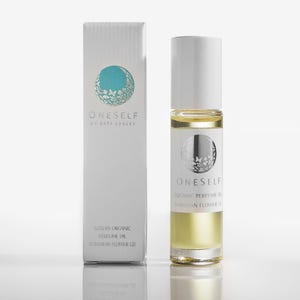 Puede incluir: Una botella de perfume de vidrio transparente y su caja a juego. La botella tiene una tapa blanca y una etiqueta con el texto "ONESELF" y "ORGANIC PERFUME OIL HAWAIIAN FLOWER LEI". La caja tiene el mismo logotipo y texto.