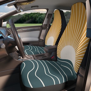 May include: A pair of car seat covers with a teal and white wavy pattern. The driver's seat cover features a yellow and white sunburst design.