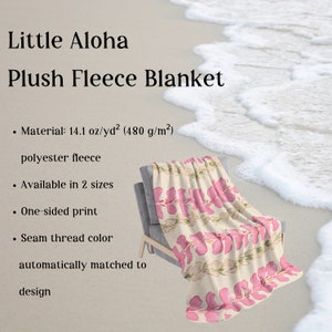 May include: A plush fleece blanket with a floral print featuring pink hibiscus flowers on a cream background. The blanket is folded and displayed on a chair. The text "Little Aloha Plush Fleece Blanket" is visible at the top of the image. The text "Material: 14.1 oz/yd&sup2; (480 g/m&sup2;) polyester fleece" is visible below the image. The text "Available in 2 sizes" is visible below the image. The text "One-sided print" is visible below the image. The text "Seam thread color automatically matched to design" is visible below the image.
