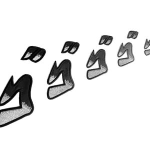 May include: A series of stylized black and silver Japanese manga sound effect patches. The patches are in a diagonal arrangement, with a white background. The patches are embroidered with a black outline and silver fill.