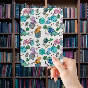 May include: A white tablet case with a repeating pattern of colourful dinosaurs, dice, and tropical leaves. The dinosaurs are in shades of pink, purple, orange, green, and blue. The dice are various colours and shapes.